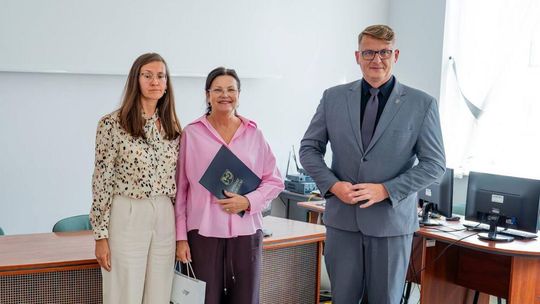 dwie kobiety i mężczyzna stojący przed biurkiem