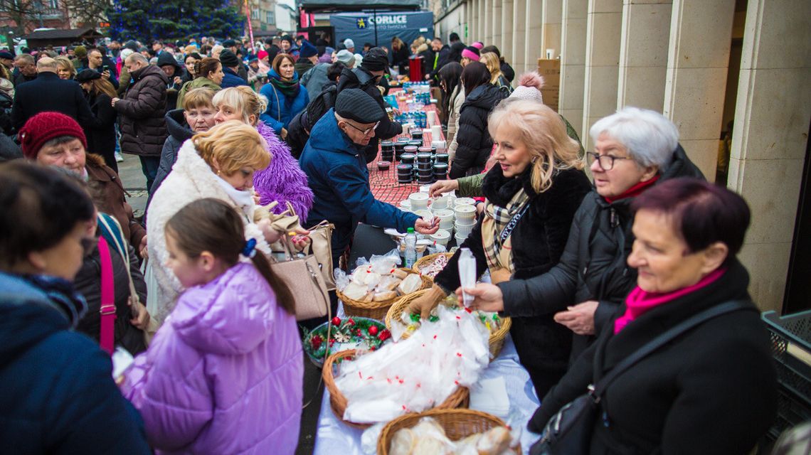zdjęcie przedstawia grupę osób przy stole wigilijnym na rynku miasta