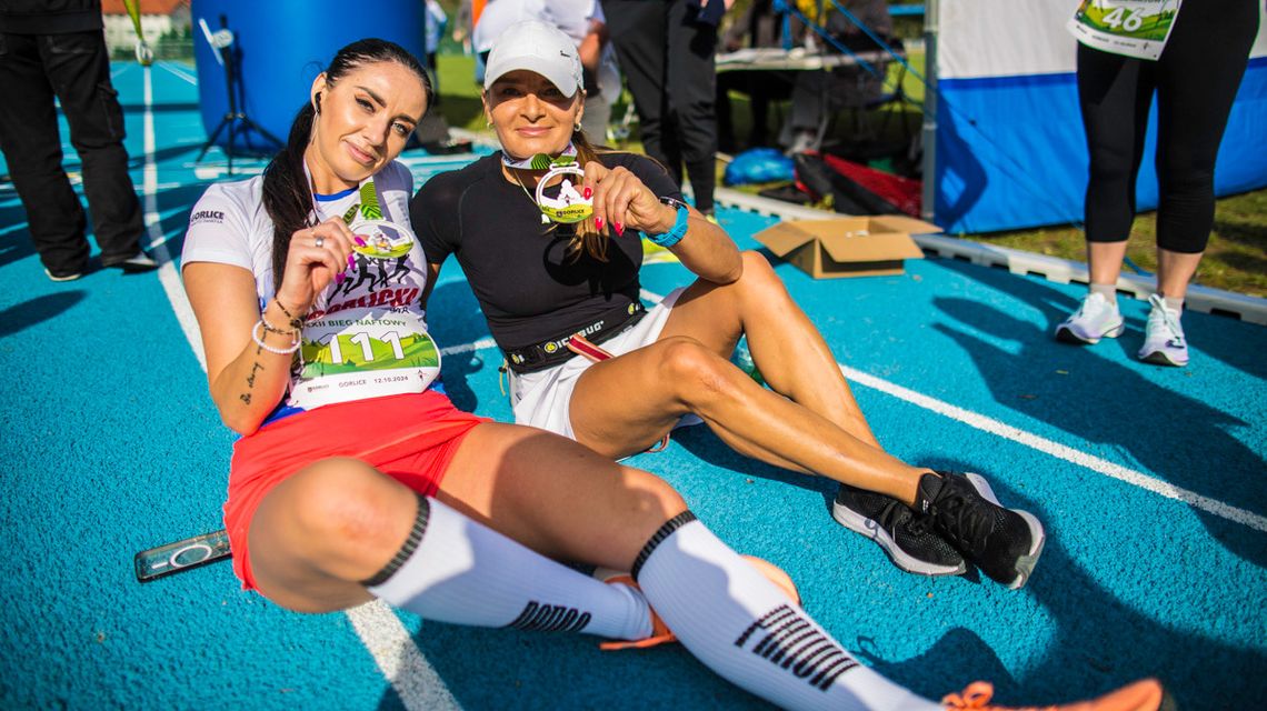 dwie kobiety siedzące na bieżni z medalami na szyi