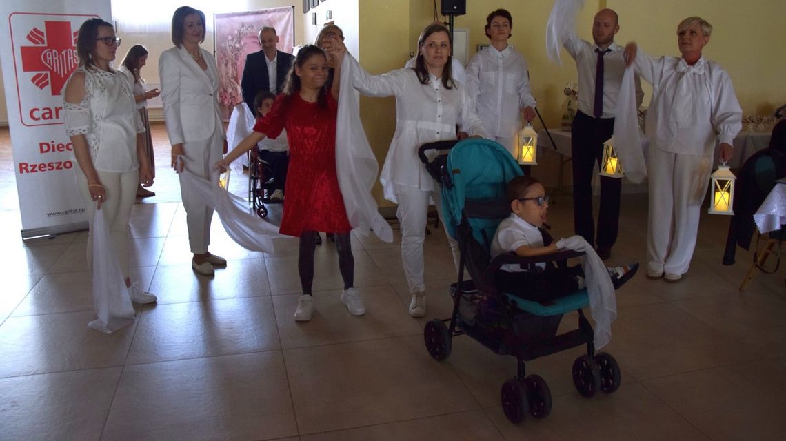 zdjęcie przedstawia grupę osób, które stoją z podniesionymi rękami trzymając białe chusty