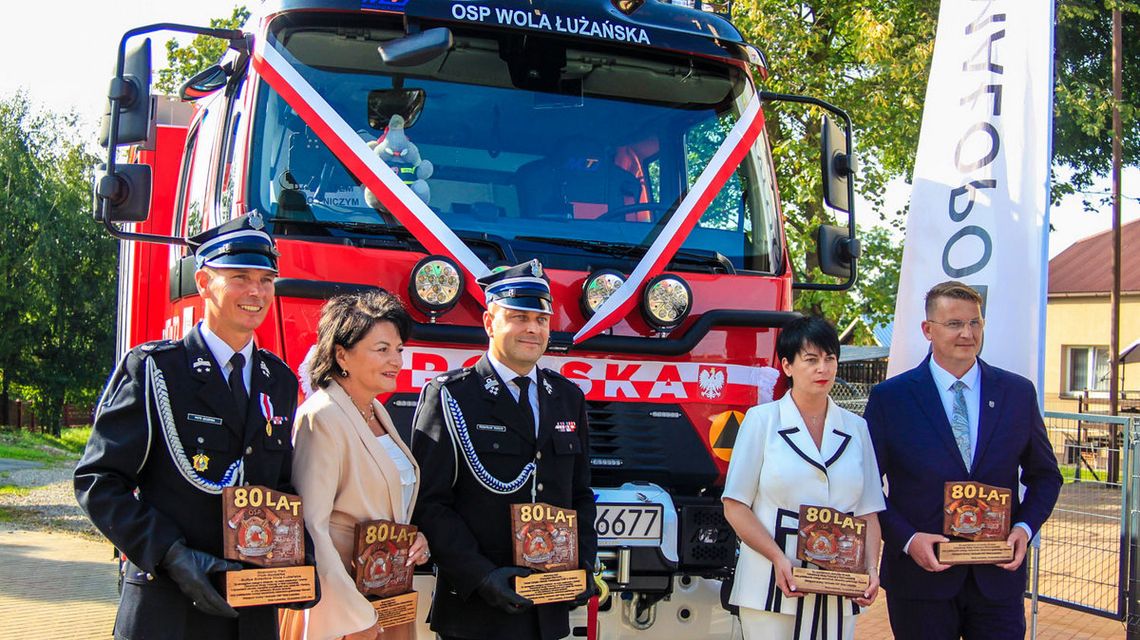 zdjęcie przedstawia kilka osób przed samochodem straży pożarnej