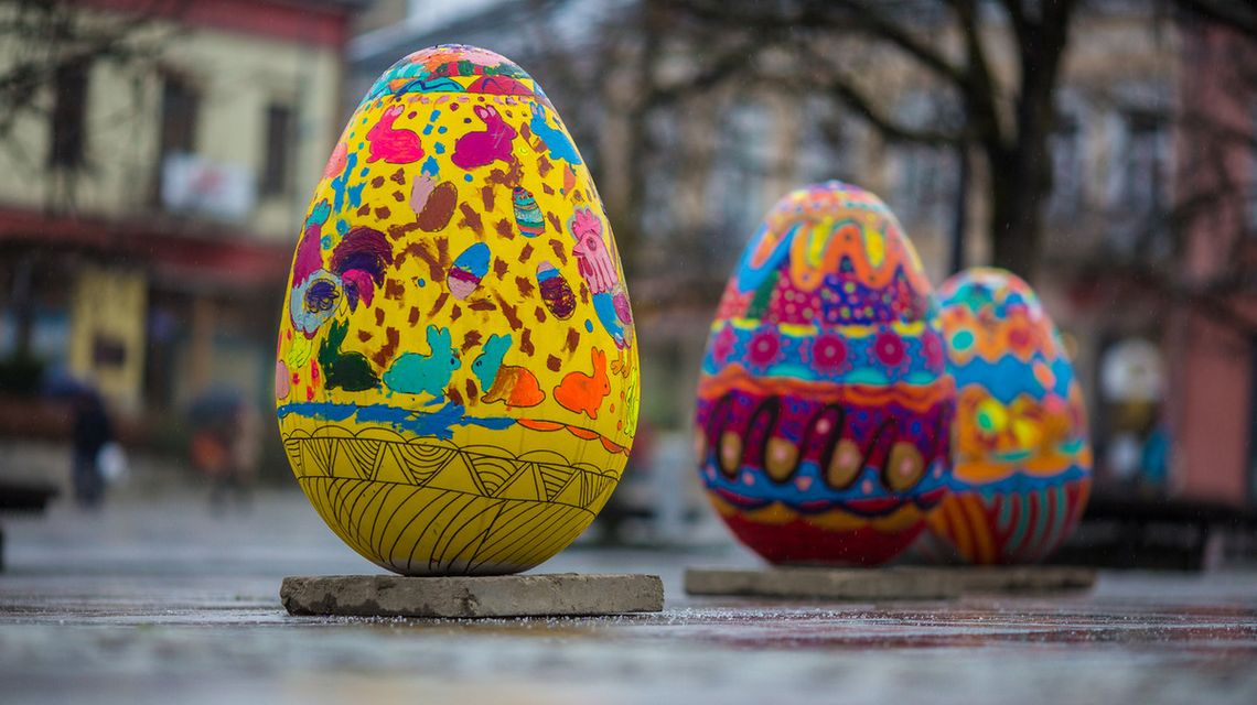 zdjęcie przedstawia pokolorowane makiety jajek ustawione na placu rynku w mieście