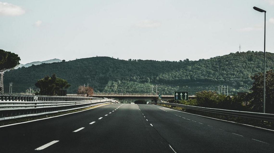 zdjęcie przedstawia autostradę, w dali wzniesienie obrośnięte lasem