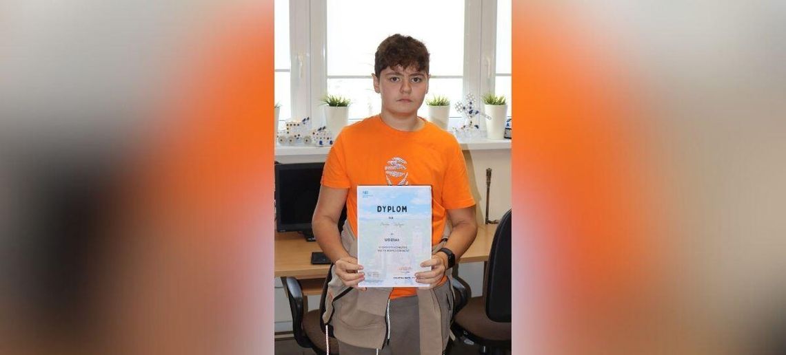 zdjęcie przedstawia chłopaka trzymającego dyplom