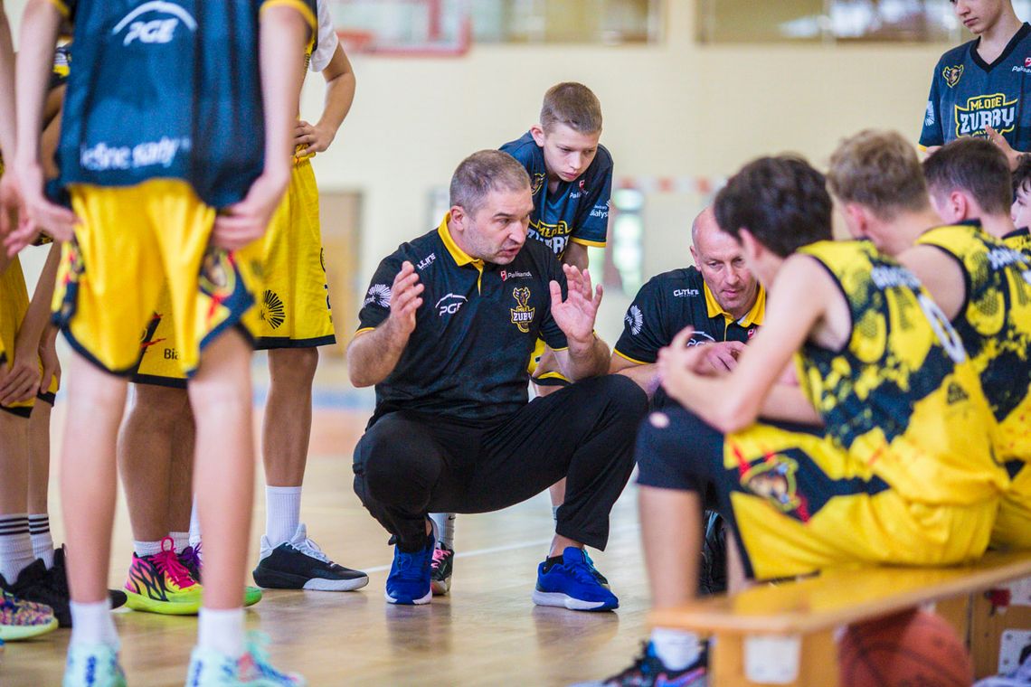 Trener siedzący przed zawodnikami tłumaczący im zagranie w koszykówce