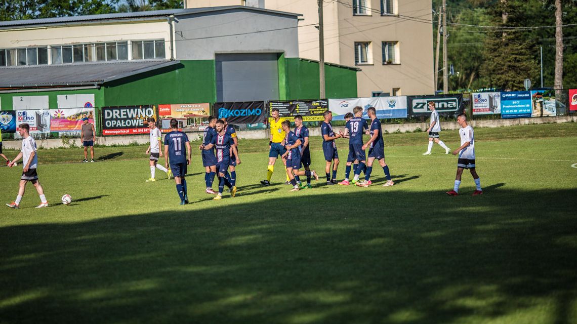 grupa mężczyzn w jednolitych koszulkach sportowych na środku boiska sportowego