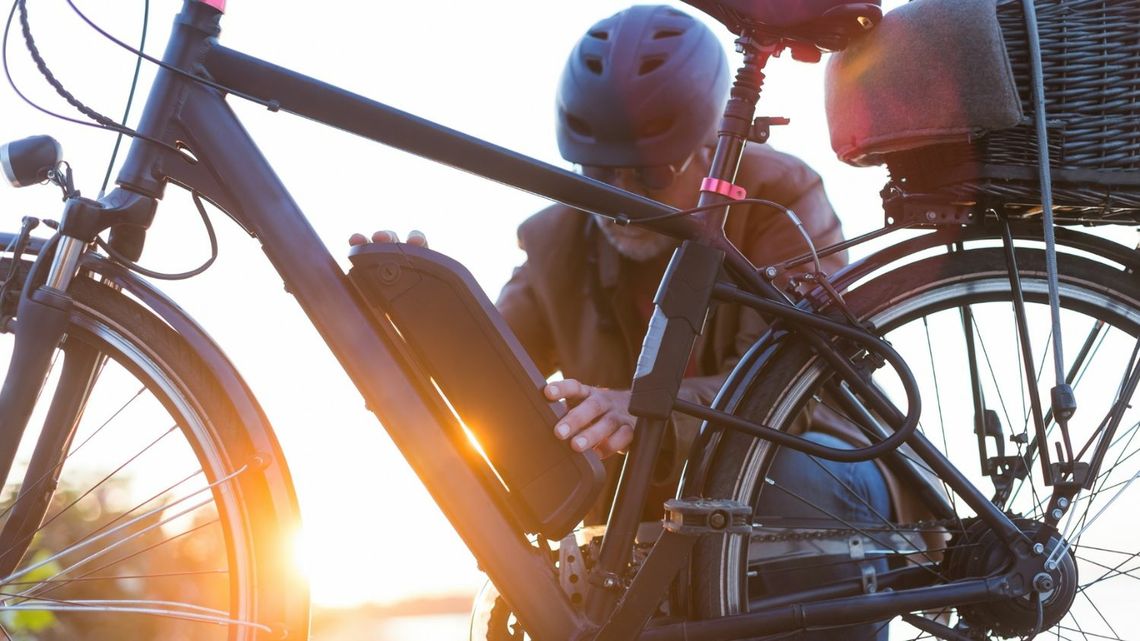 Senior wymienia baterię w swoim miejskim rowerze elektrycznym