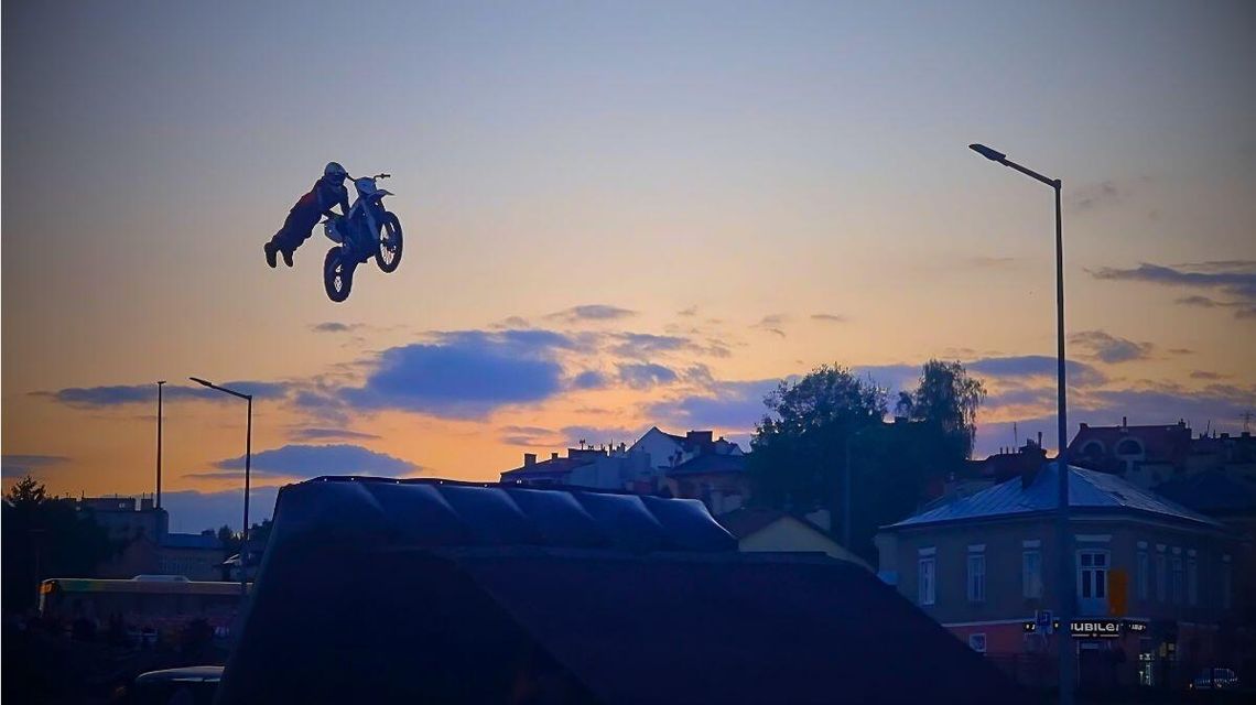 zdjęcie przedstawia mężczyznę na motocyklu skaczącego nad rampą