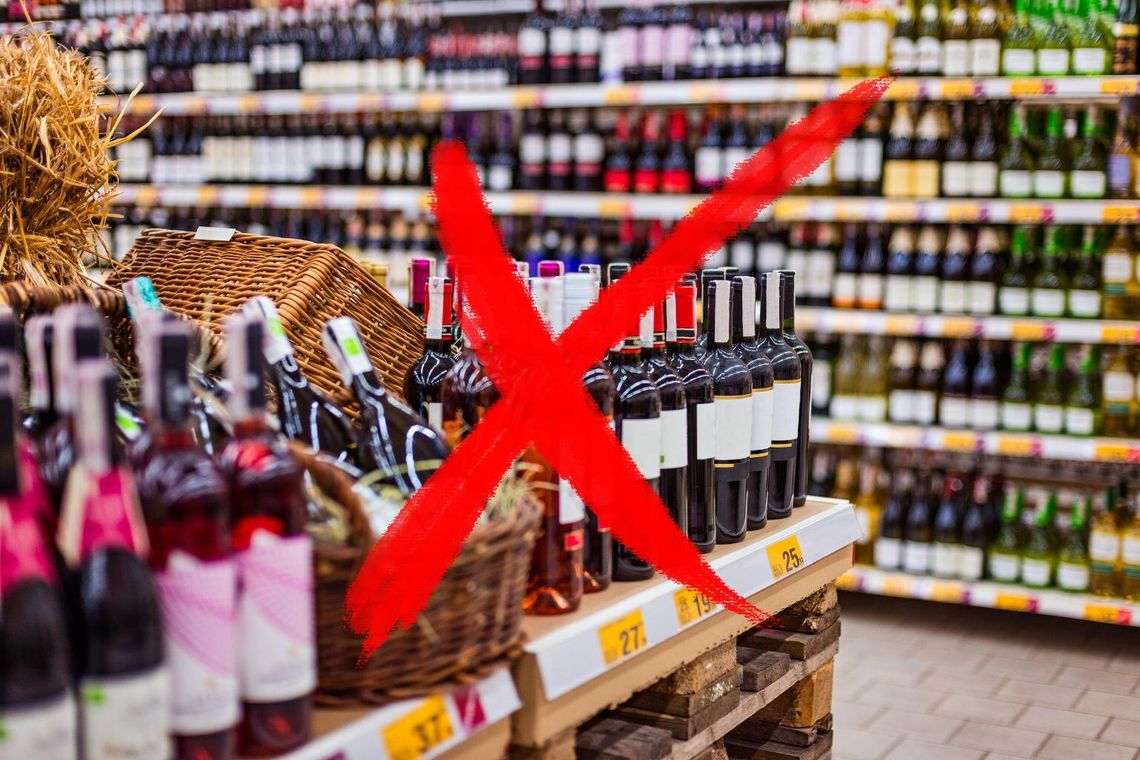 Czy Gorlice będą testować nocny zakaz sprzedaży alkoholu między godz. 22–6? Skołyszyn już to robi zdjęcie przedstawia wnętrze sklepu z butelkami alkoholu na półkach i czerwony krzyż na pierwszym planie