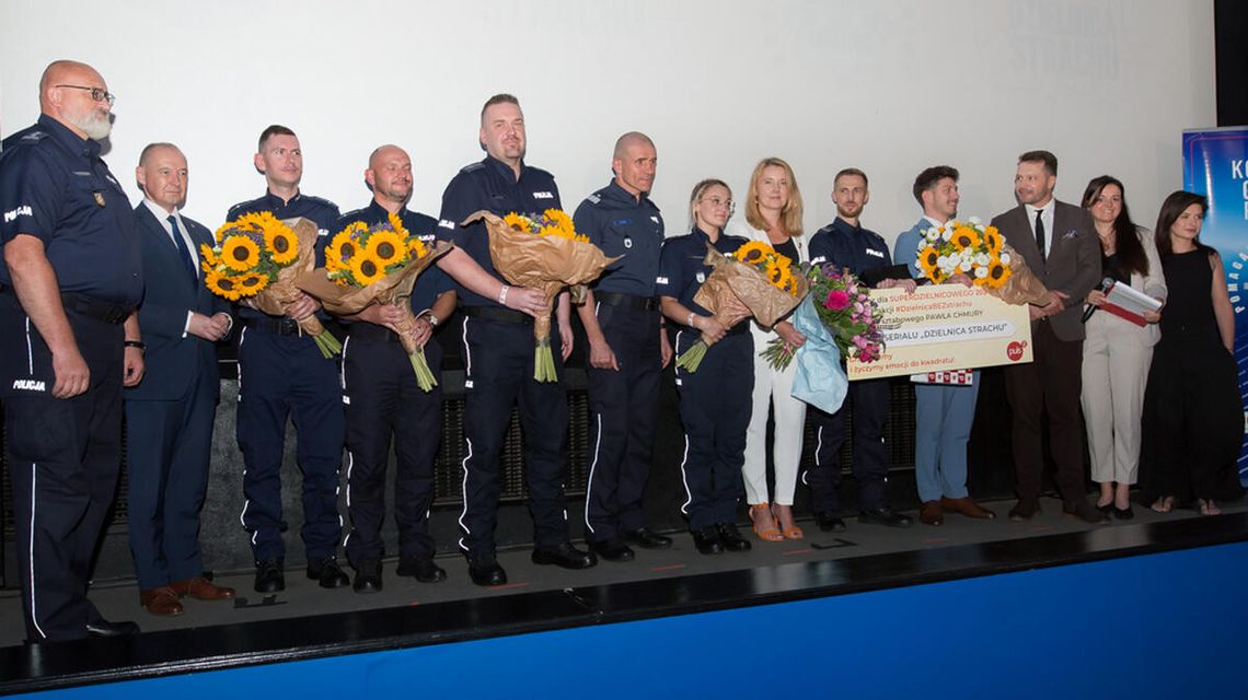 zdjęcie przedstawia policjantów z kwiatami na scenie