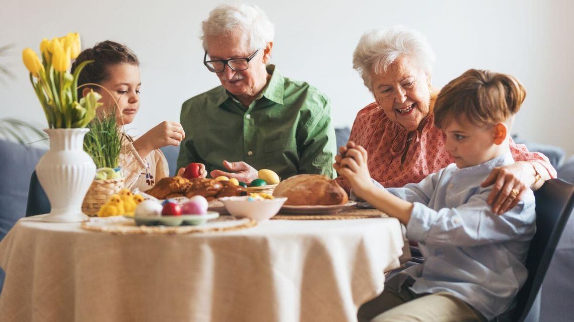 Dawne zwyczaje kontra nowoczesność. Czy Wielkanoc się zmienia? zdjęcie przedstawia babcię i dziadka przy stole siedzących z wnukami
