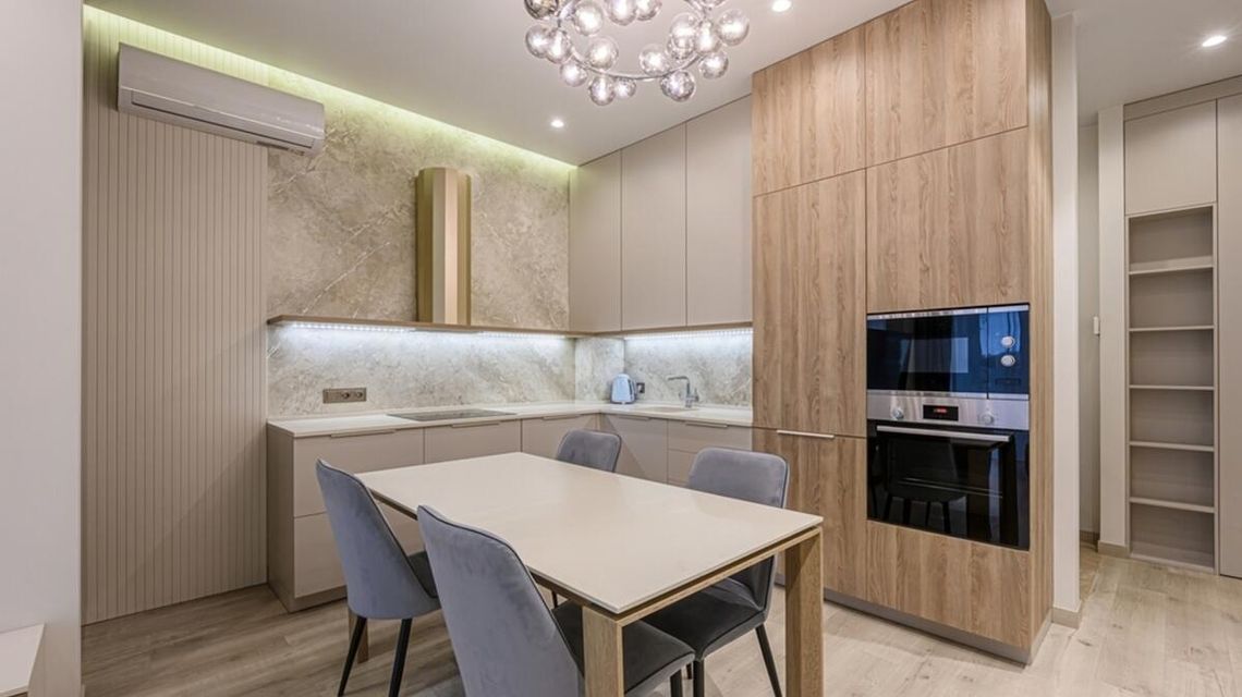 Dlaczego krzesła szare pasują do każdego stylu wnętrzarskiego? zdjęcie przedstawia wnętrze kuchni ze stołem na środku