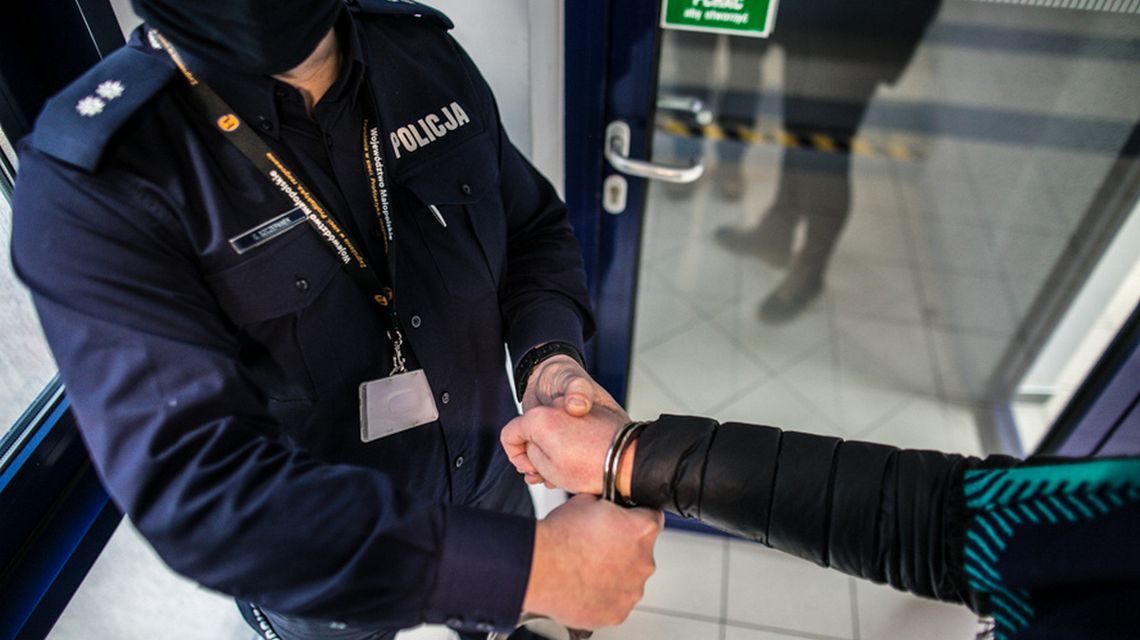 zdjęcie przedstawia policjanta zakładającego kajdanki na dłoń