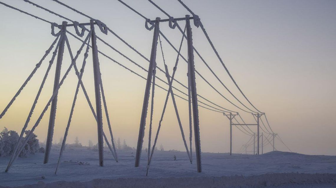 zdjęcie przedstawia słup energetyczny i linie energetyczne oblepione śniegiem