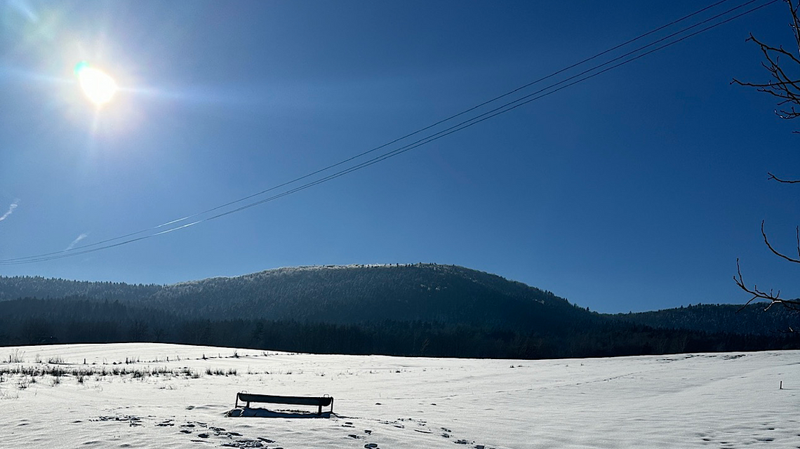 Regietów. Łąka zimą, przysypana śniegiem z „ławeczką” po środku, widok na góry