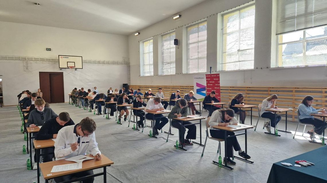 zdjęcie przedstawia sale z uczniami piszącymi przy biurkach