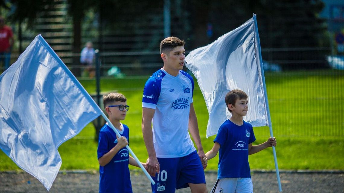 zdjęcie przedstawia piłkarza który wchodzi na mecz w asyście dzieci