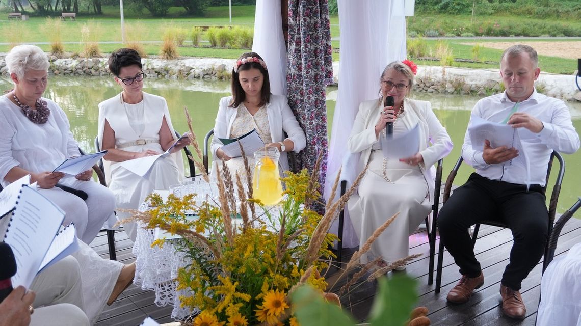 zdjęcie przedstawia osoby siedzące obok siebie na krzesełkach trzymające książki przed sobą