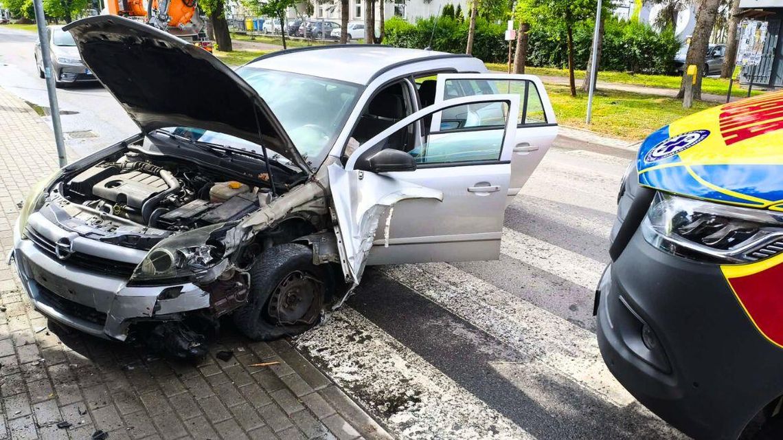 Zdjęcie przedstawia roztrzaskany samochód oraz karetkę pogotowia