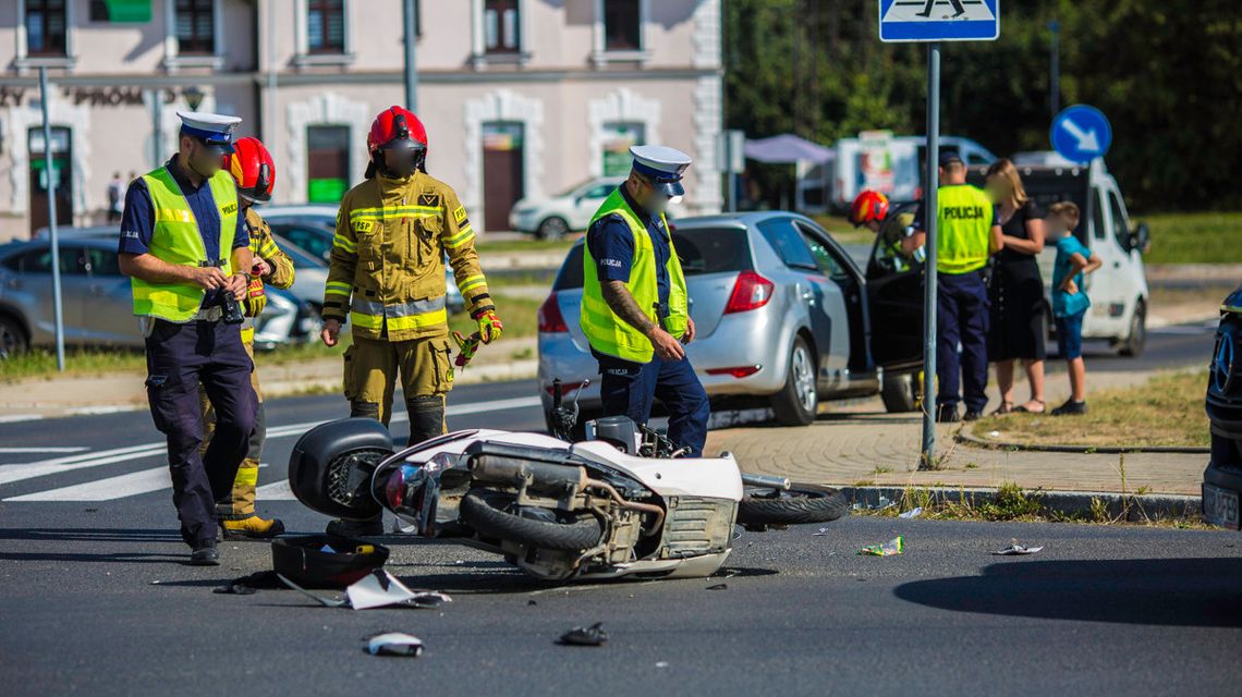 uszkodzony skuter na jezdni obok stoją policjanci i strażacy