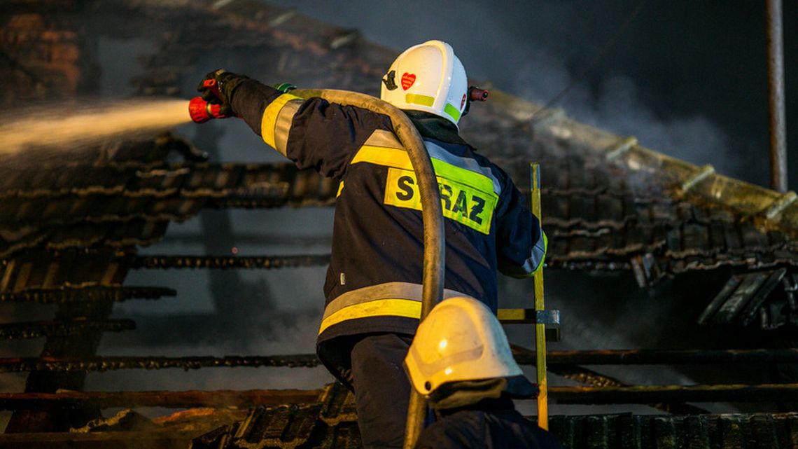 strażak w hełmie gaszący dach budynku