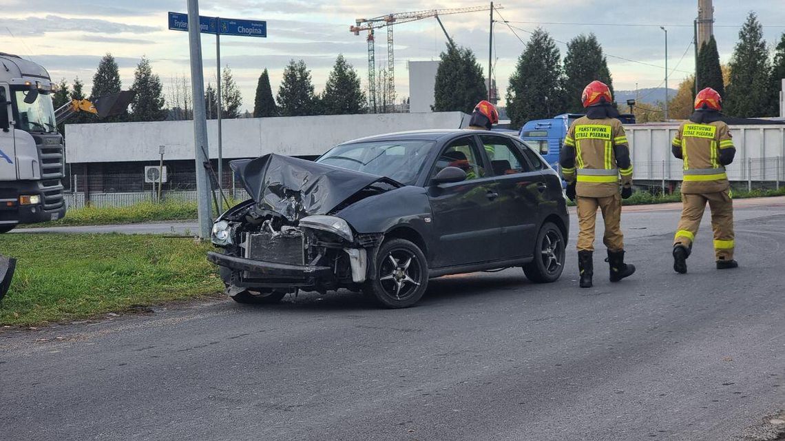 zdjęcie przedstawia rozbitą karoserię samochodu i strażaków wokół pojazdu