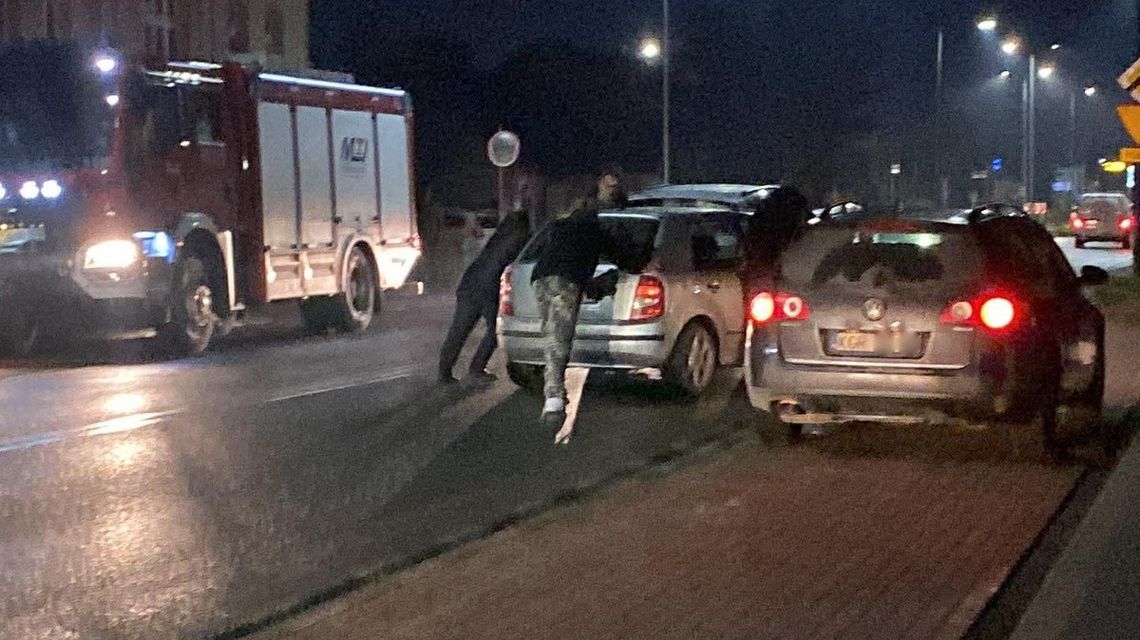 zdjęcie przedstawia dwa samochody na jezdni obok samochód straży pożarnej