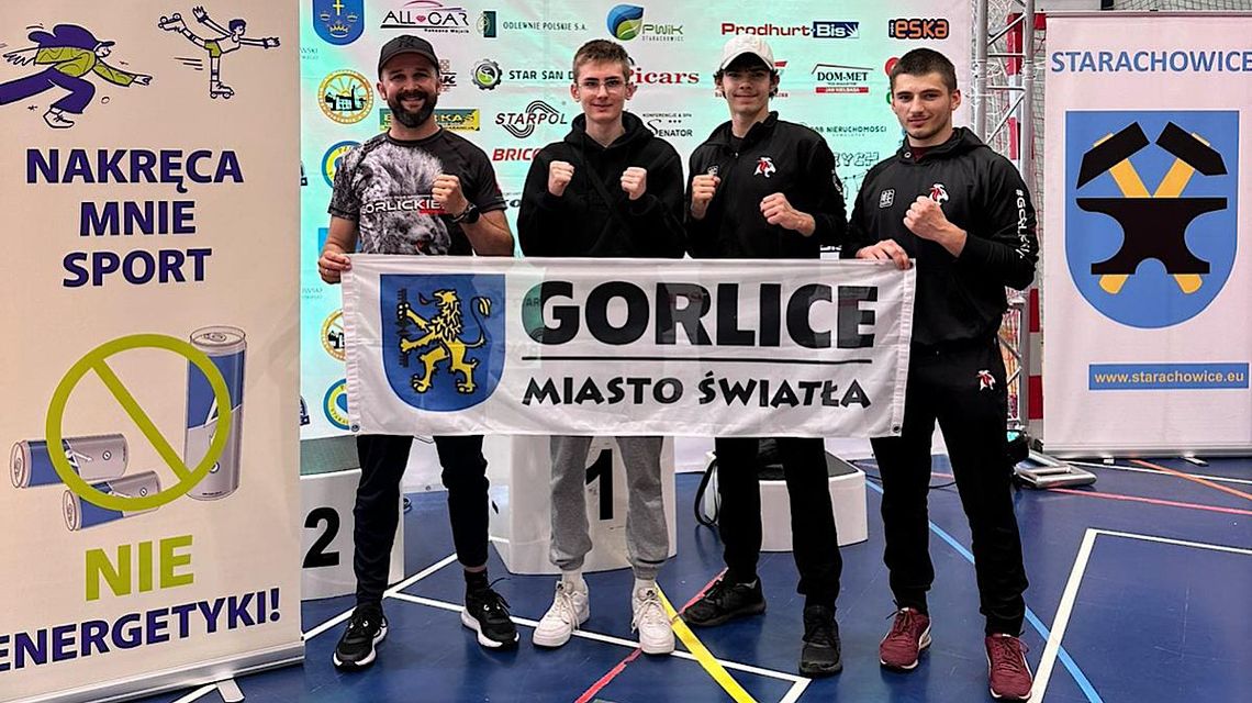 Czterech członków grupy kickboxingowej – „Gorlickie Lwy”, trzymają baner z napisem „Gorlice Miasto Światła”