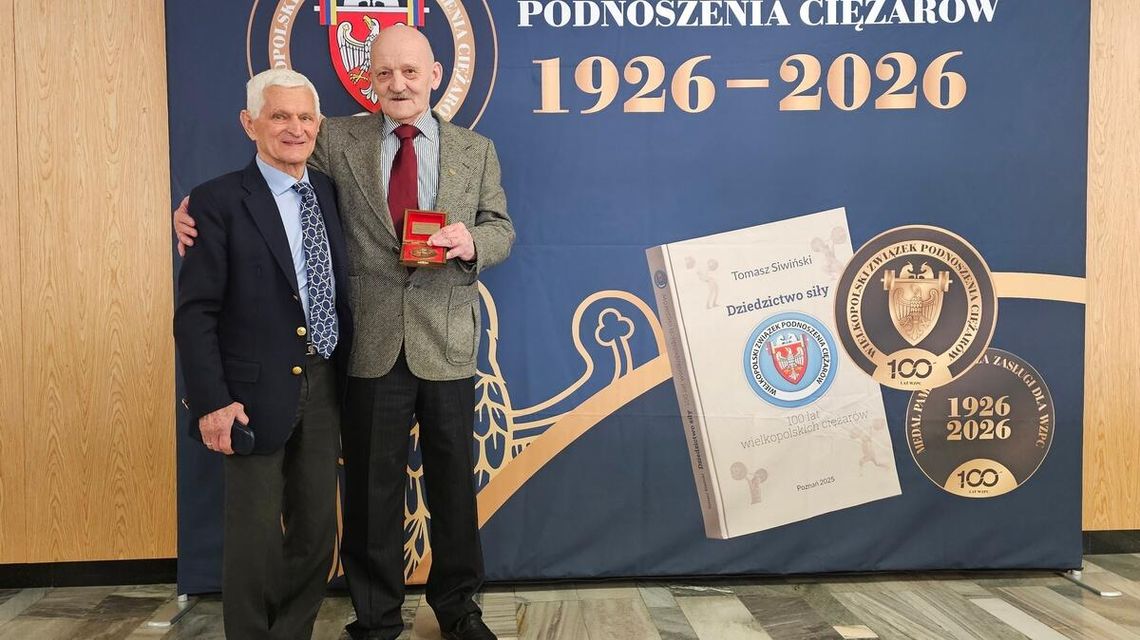 zdjęcie przedstawia dwóch mężczyzn przed ścianką reklamową