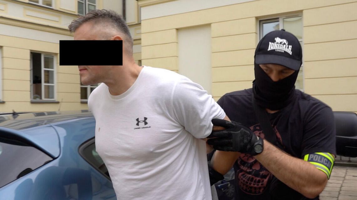 zdjęcie przedstawia mężczyznę prowadzonego przez policjanta