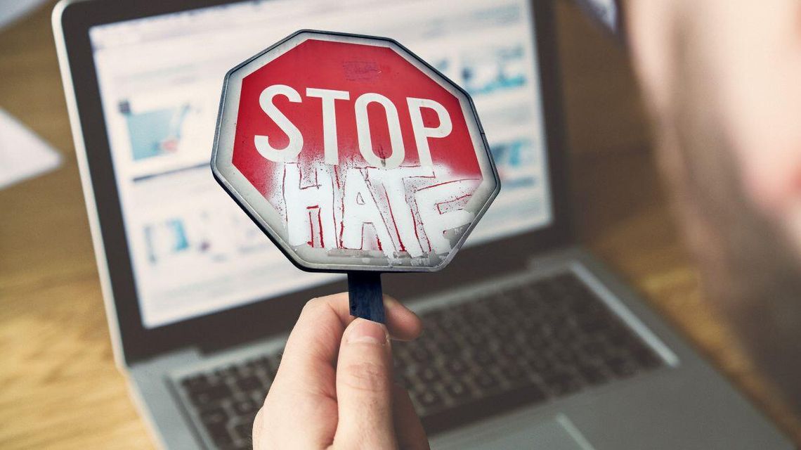 zdjęcie przedstawia rękę która trzyma lupę z napisem stop hate