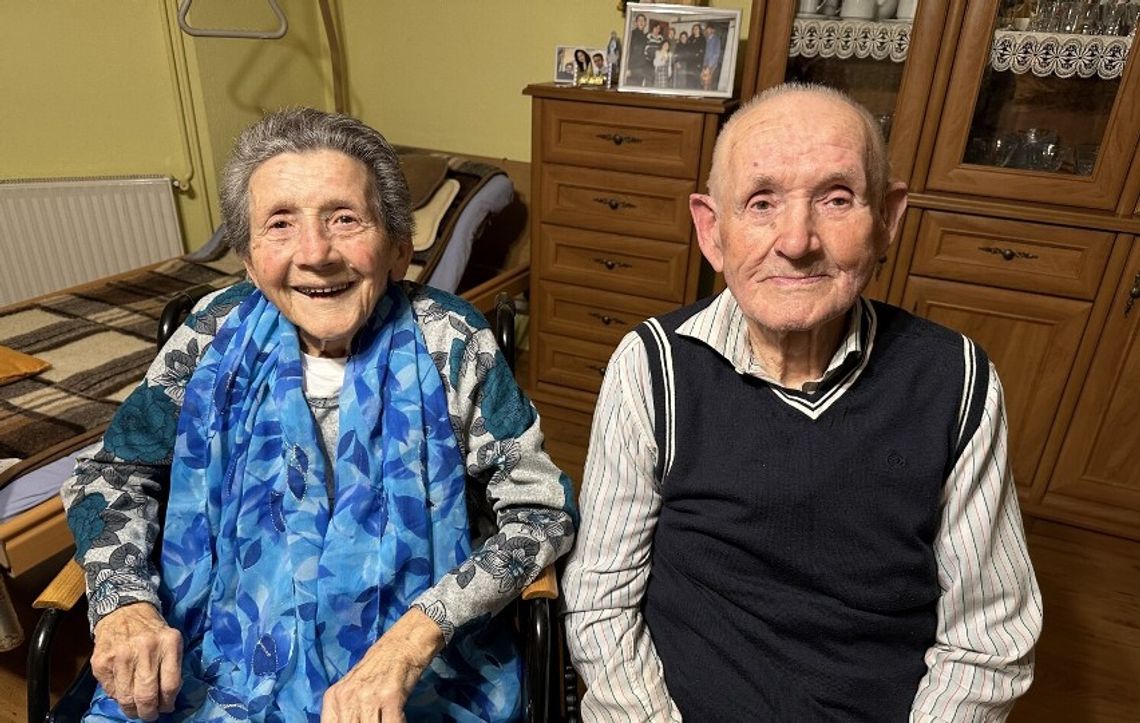 Starsza kobieta na wózku ze starszym mężczyzną, oboje uśmiechnięci