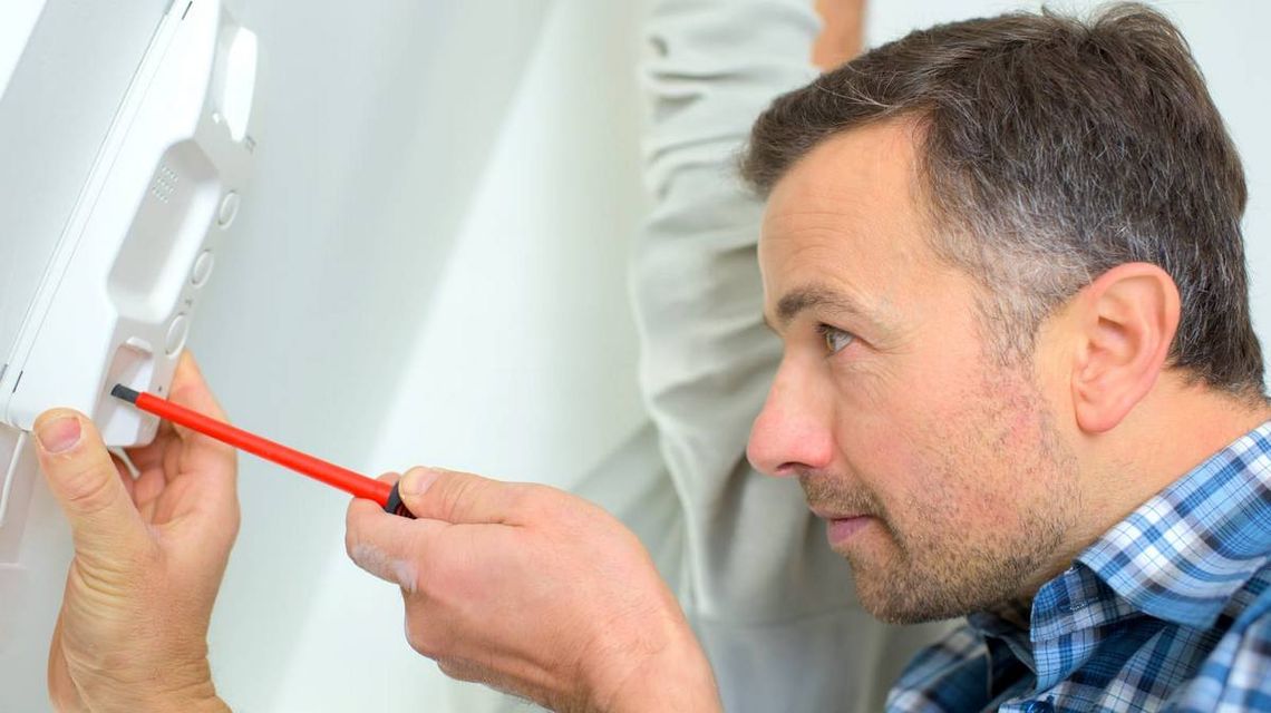 Jak wideodomofon czyni twoje życie wygodniejszym? 7 dowodów zdjęcie przedstawia mężczyznę ze śrubokrętem w dłoni
