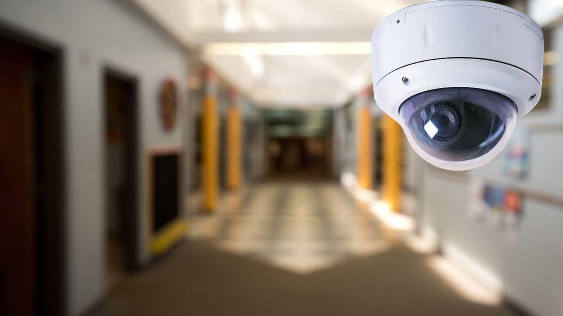 zdjęcie przedstawia kamerę monitoringu, w tle niewyraźne zdjęcie szkolnego korytarza