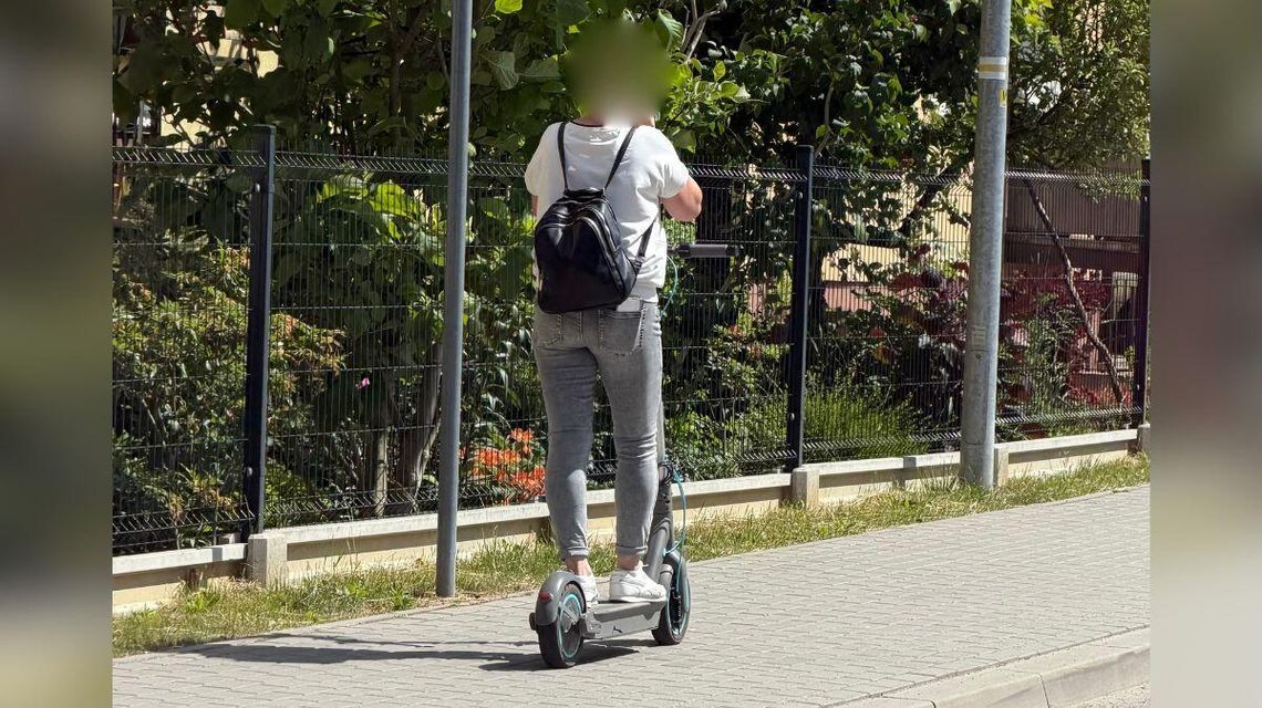 zdjęcie przedstawia osobę jadącą chodnikiem na hulajnodze