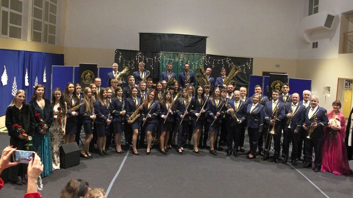 zdjęcie przedstawia dużą grupę osób w mundurach galowych i eleganckich strojach podczas koncertu