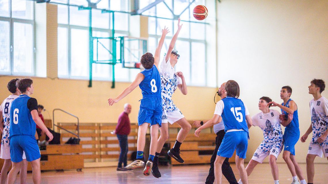 zdjęcie przedstawia koszykarzy walczących o piłkę w powietrzu