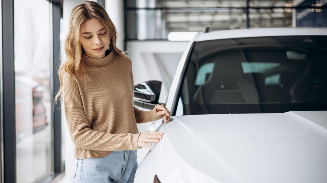 Leasing samochodu w firmie – jakie korzyści podatkowe możesz uzyskać w 2026 roku? zdjęcie przedstawia kobietę stojąca przy samochodzie