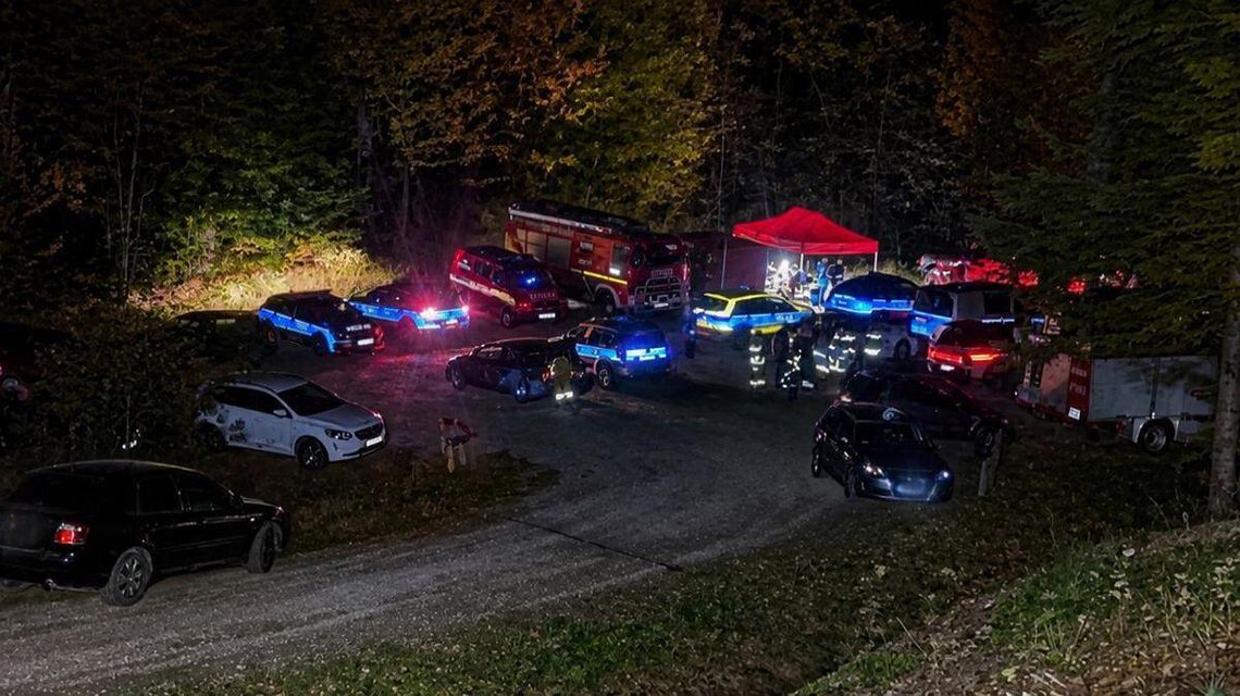 samochody policji i straży pożarnej na placu w środku lasu w nocy