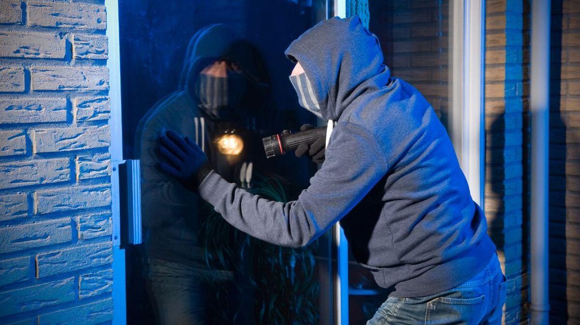 Zdjęcie przedstawia  zamaskowaną osobę z latarką