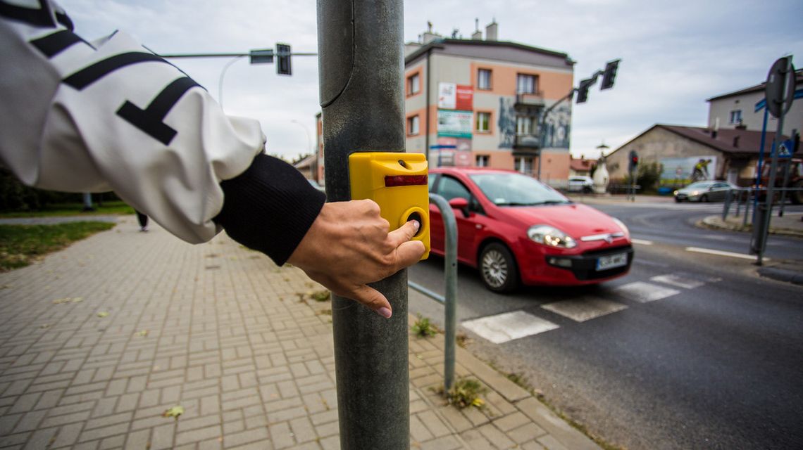 palec położony na przycisku włączający zielone światło na przejściu dla pieszych