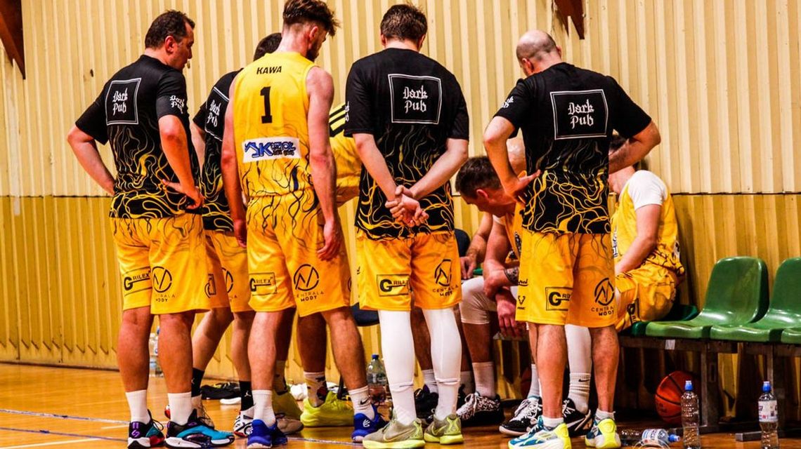 zdjęcie przedstawia kilku mężczyzn w jednolitych koszulkach sportowych stoją obok siebie w kole