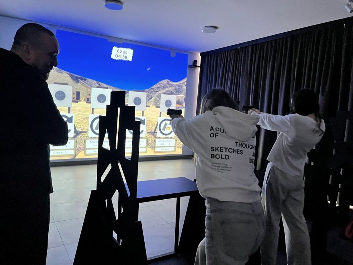 zdjęcie przedstawia ludzi w budynku strzelnicy