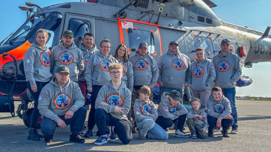 zdjęcie przedstawia grupę osób przed wojskowym helikopterem