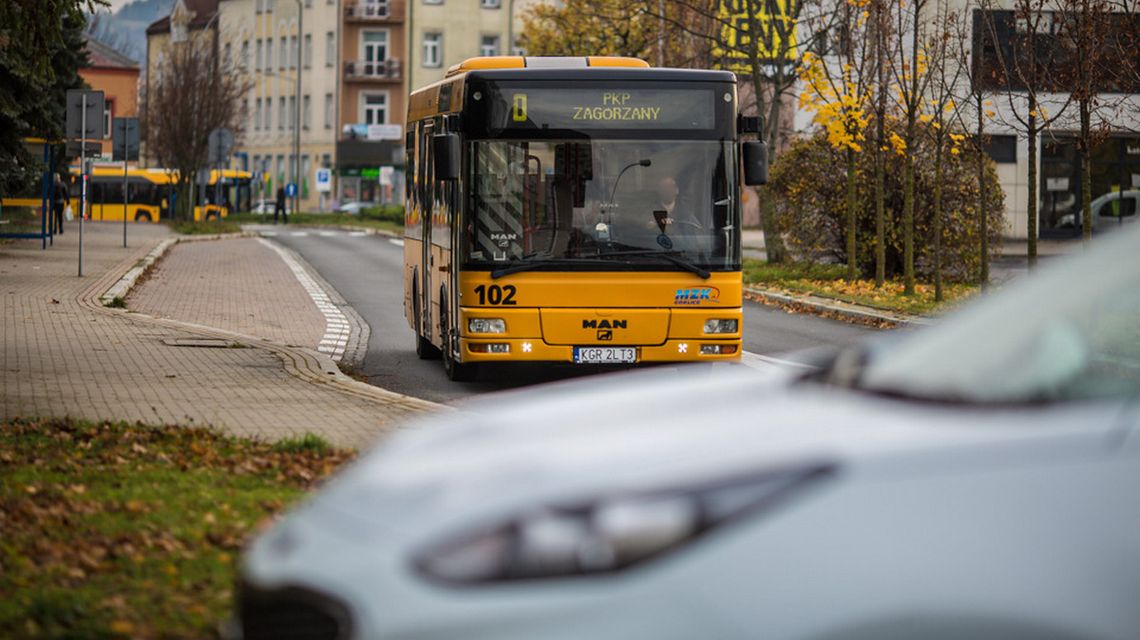 zdjęcie przedstawia żółty autobus jadący miejską ulicą