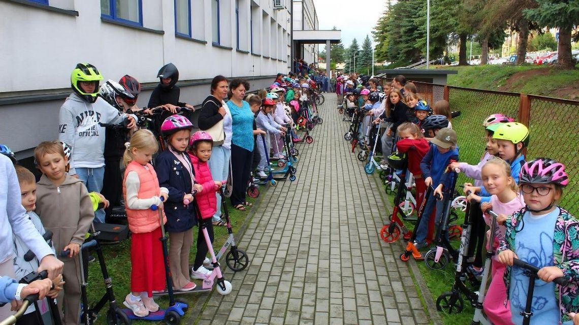 dzieci stojące po obu stronach chodnika przez szkołą nr 6 w Gorlicach, stoją razem w hulajnogami