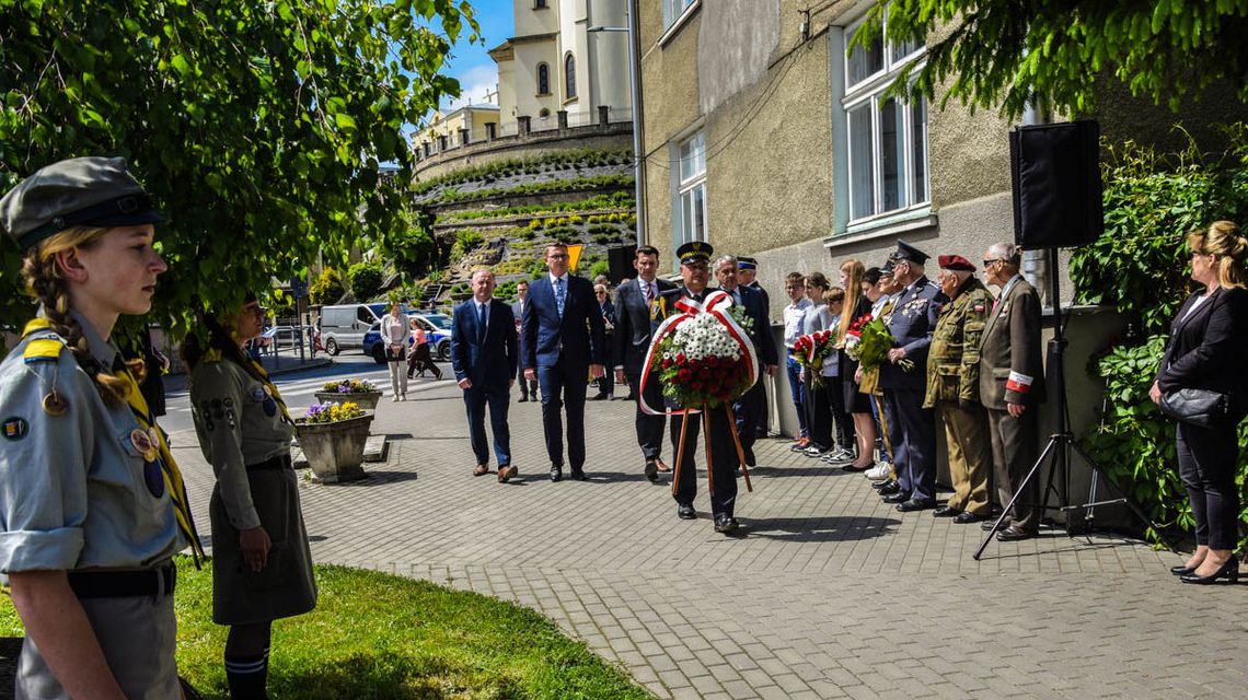 mężczyźni w garniturach niosą kwiaty na miejsce pamięci pod budynkiem sklarczykówki w gorlicach