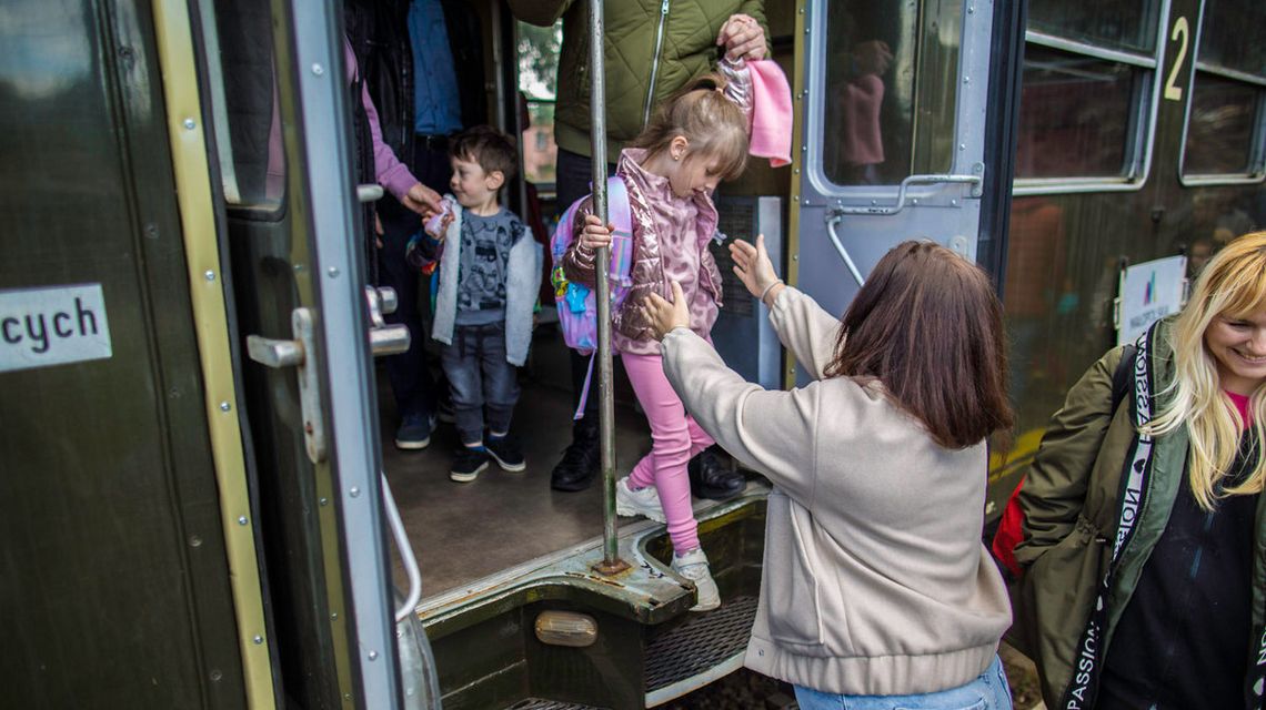 zdjęcie przedstawia dziecko wysiadające z pociągu