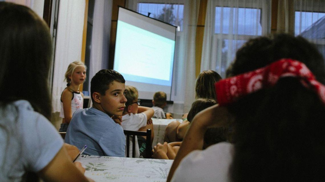 Ostatnie tygodnie wakacji – jak je spędzić i jak przygotować dziecko na ich koniec? chłopiec siedzący na krześle i oglądający się do tył, za nim ekran
