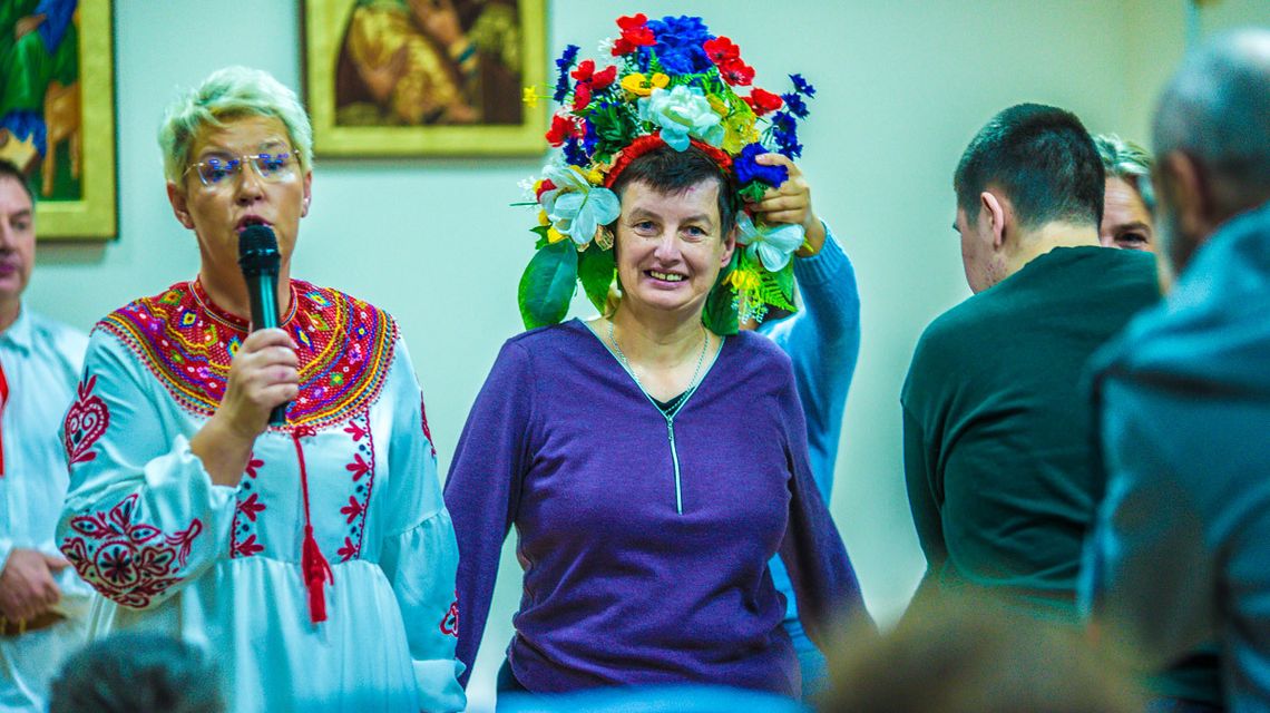 zdjęcie przedstawia kobietę w wianku na głowie, obok druga kobieta trzyma mikrofon
